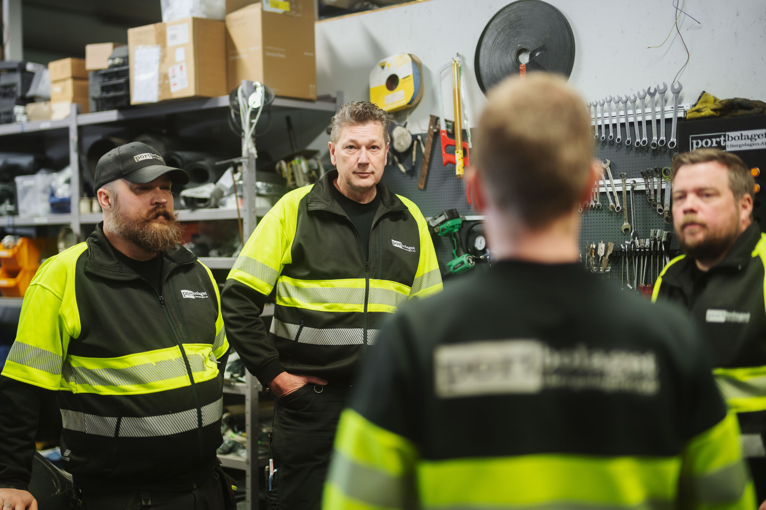 Fyra medarbetare från Portbolaget i Bergslagen i samtal i en verkstadsmiljö.